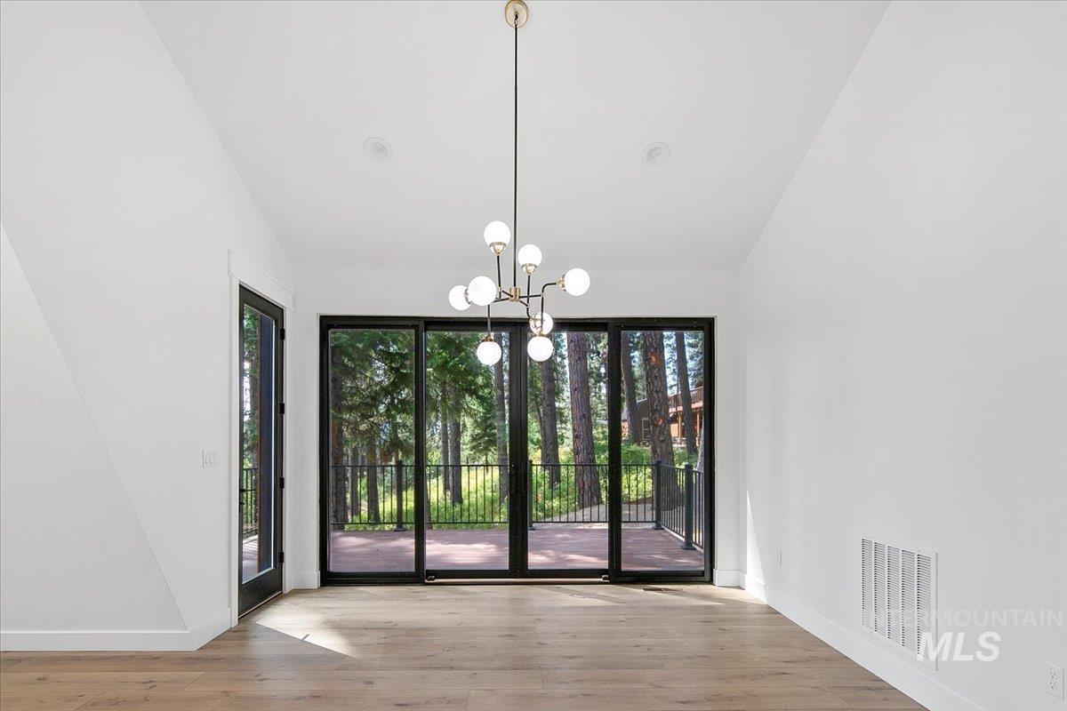 Unfurnished dining area with a chandelier, lofted ceiling, and wood finished floors