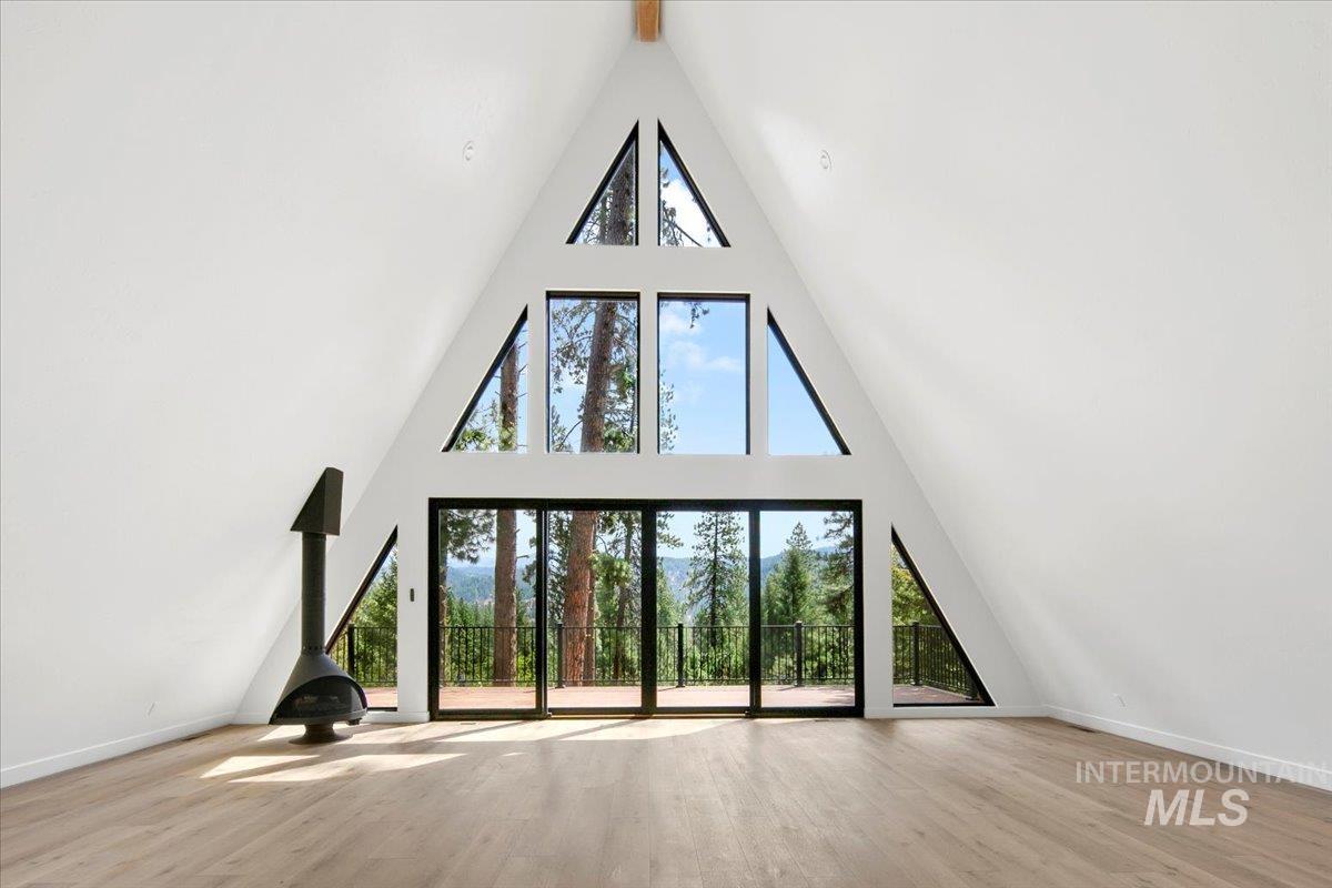 Unfurnished living room with high vaulted ceiling and wood finished floors