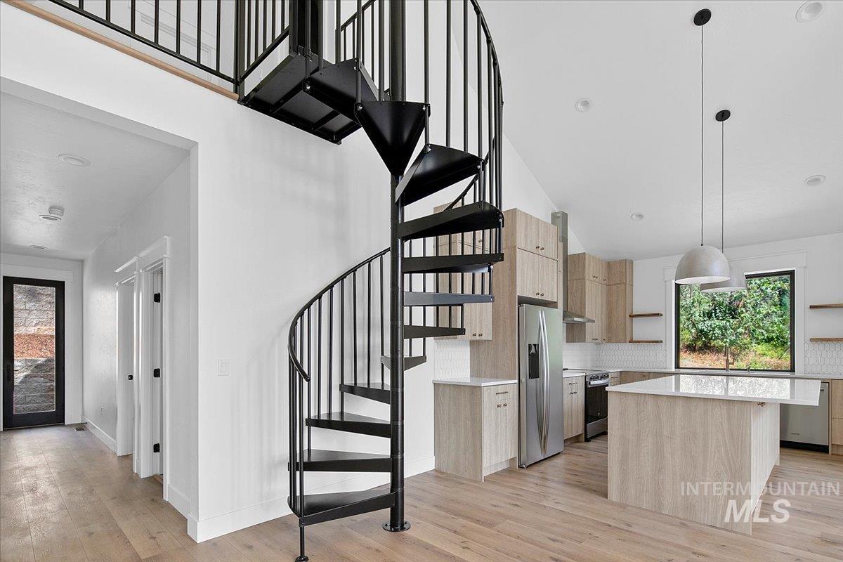 Stairs with a towering ceiling and wood finished floors