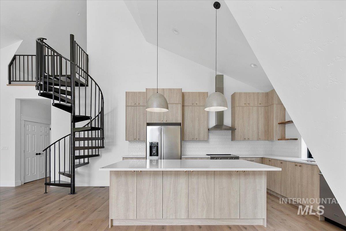 Kitchen with light brown cabinets, modern cabinets, stainless steel fridge with ice dispenser, and a kitchen island