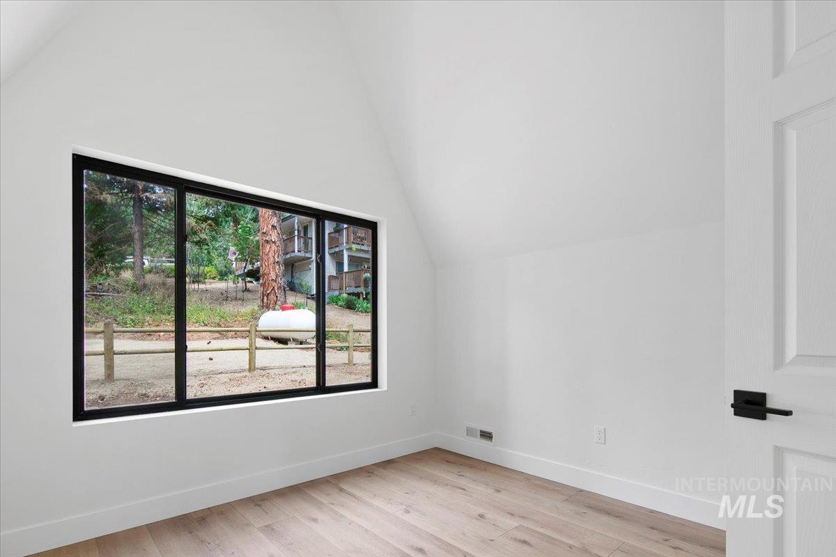 Bedroom with lofted ceiling and light wood finished floors