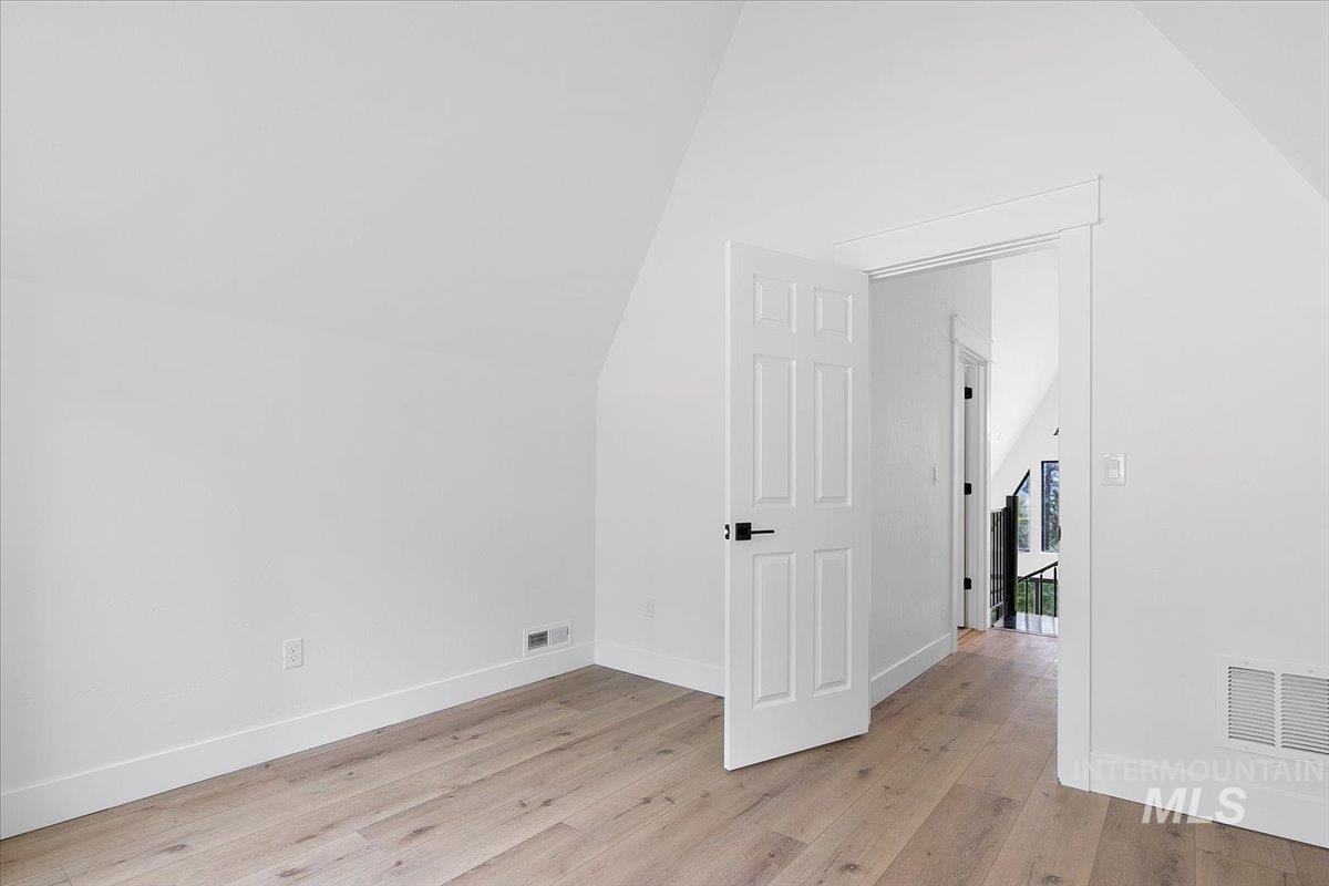 Bedroom featuring light wood-type flooring and lofted ceiling