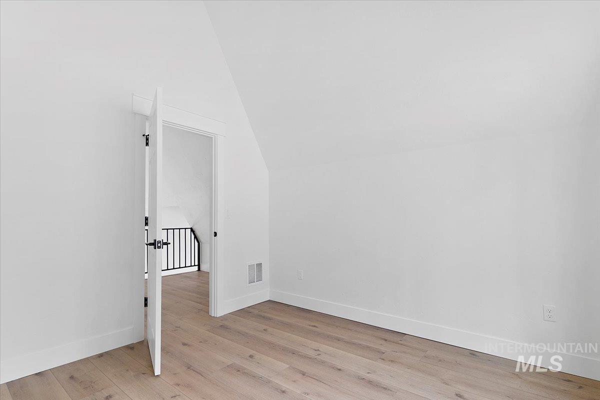 Unfurnished room with light wood-style floors and lofted ceiling