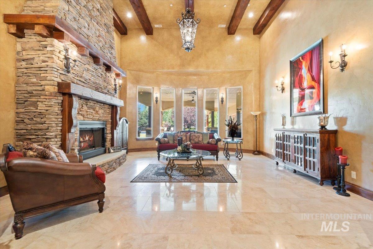 Living area with beamed ceiling, a towering ceiling, a fireplace, and recessed lighting