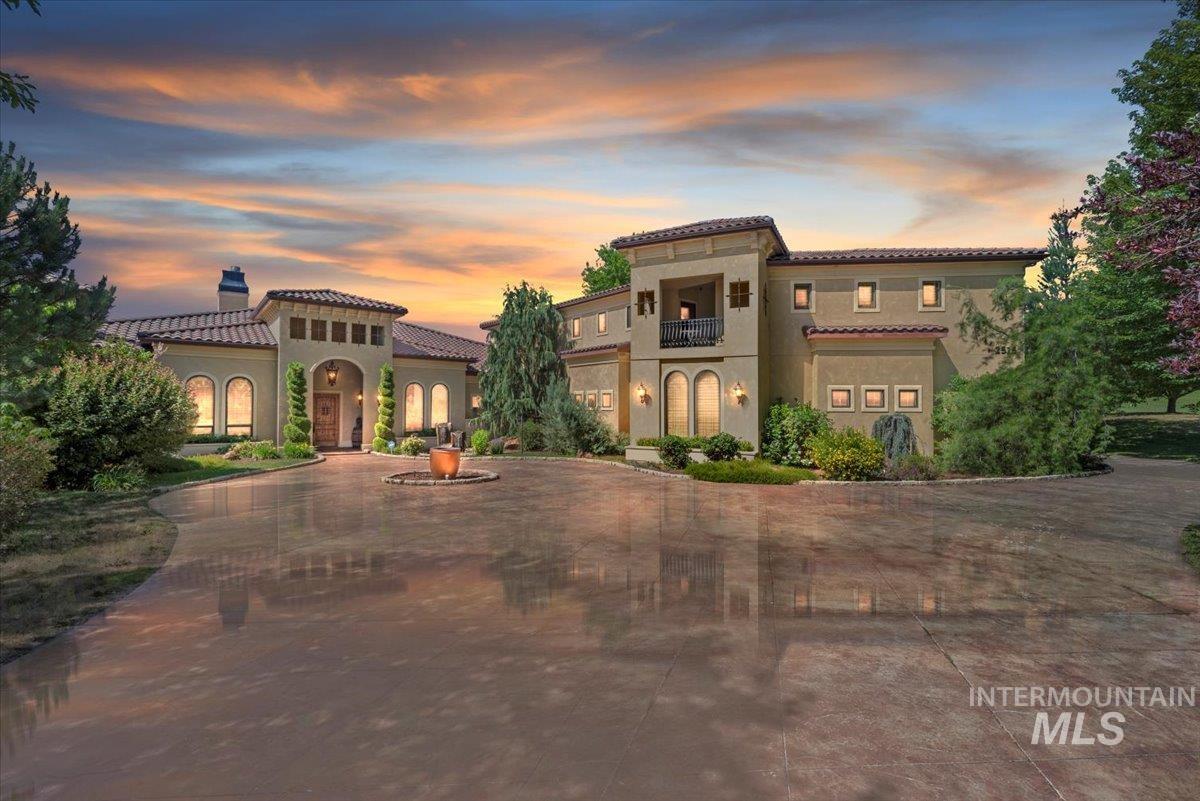 Mediterranean / spanish house featuring a tiled roof, a balcony, a chimney, stucco siding, and curved driveway