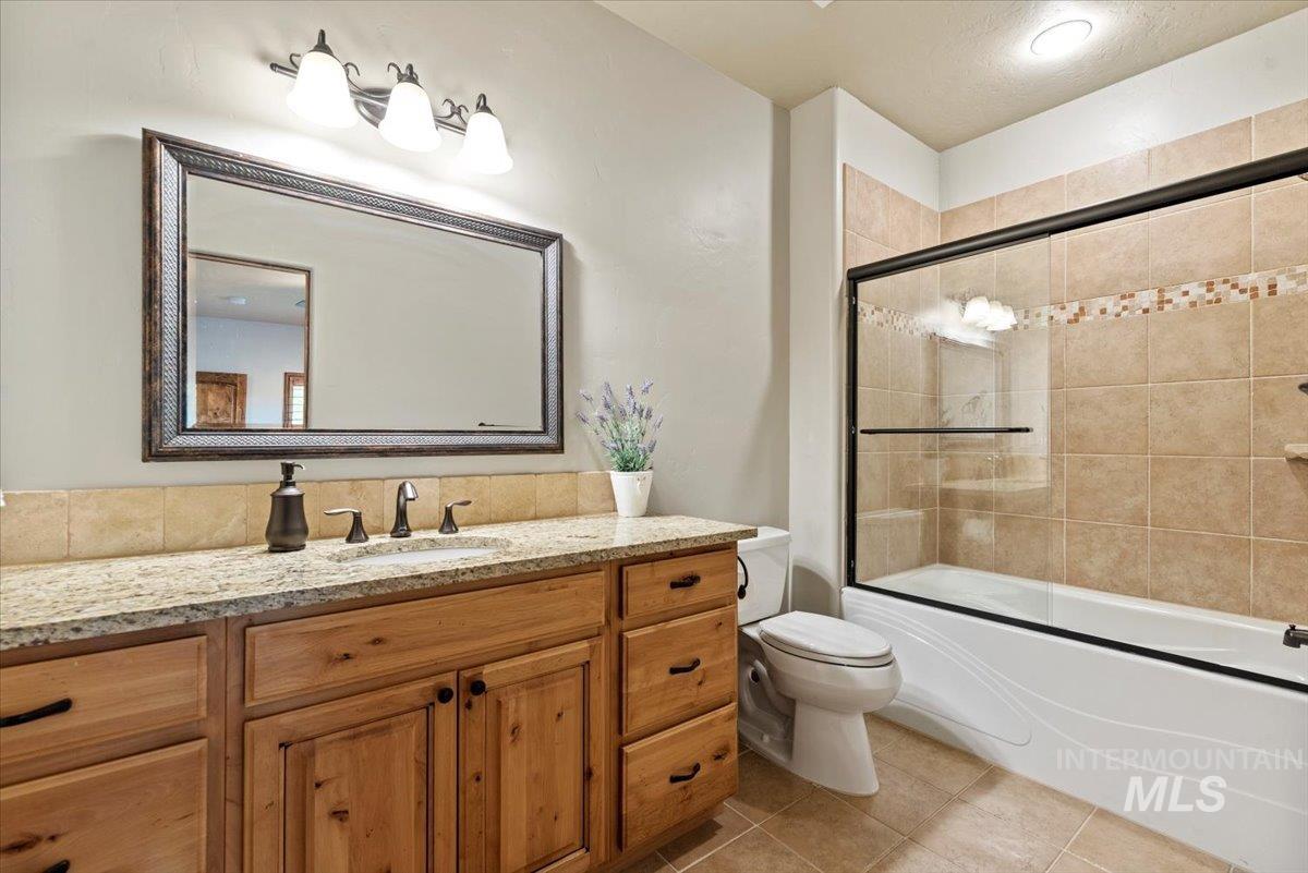 Bathroom with vanity, combined bath / shower with glass door, and tile patterned flooring