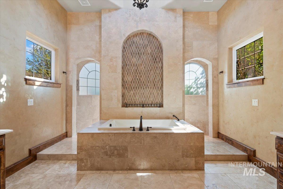 Bathroom featuring vanity, a garden tub, and healthy amount of natural light