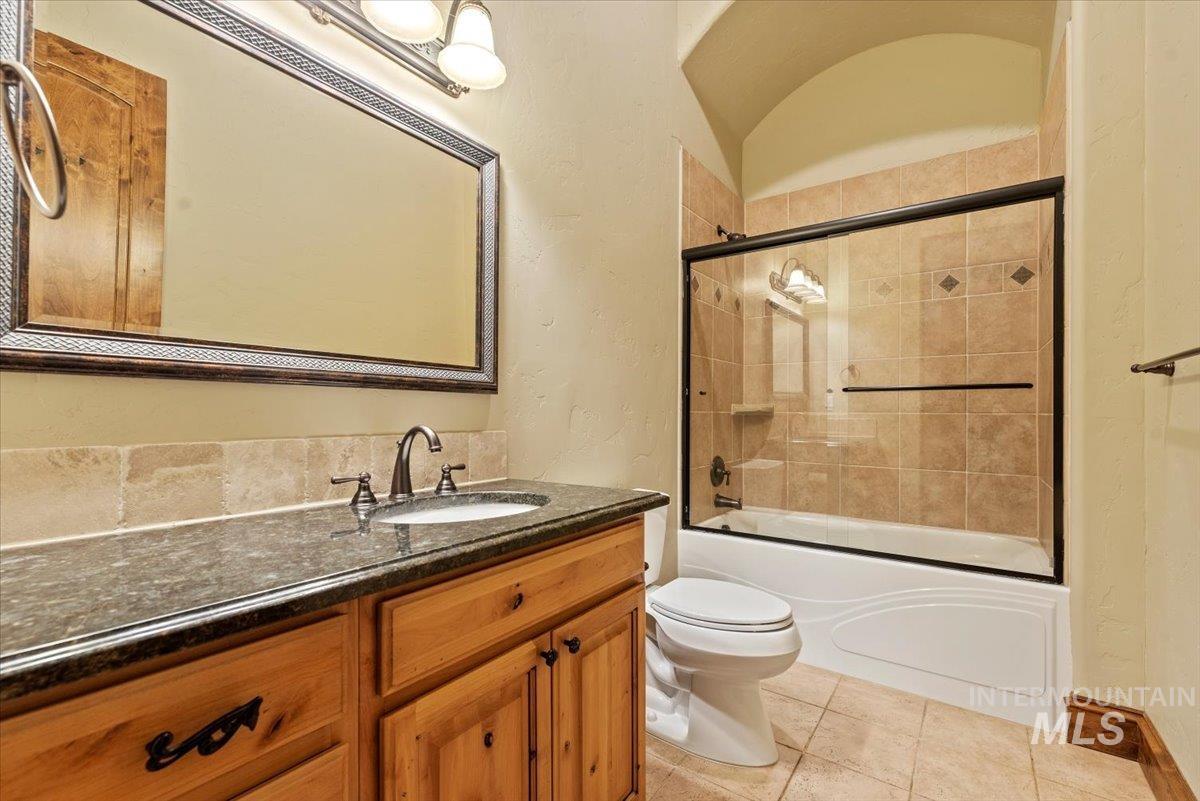 Bathroom featuring vanity, combined bath / shower with glass door, and tile patterned floors