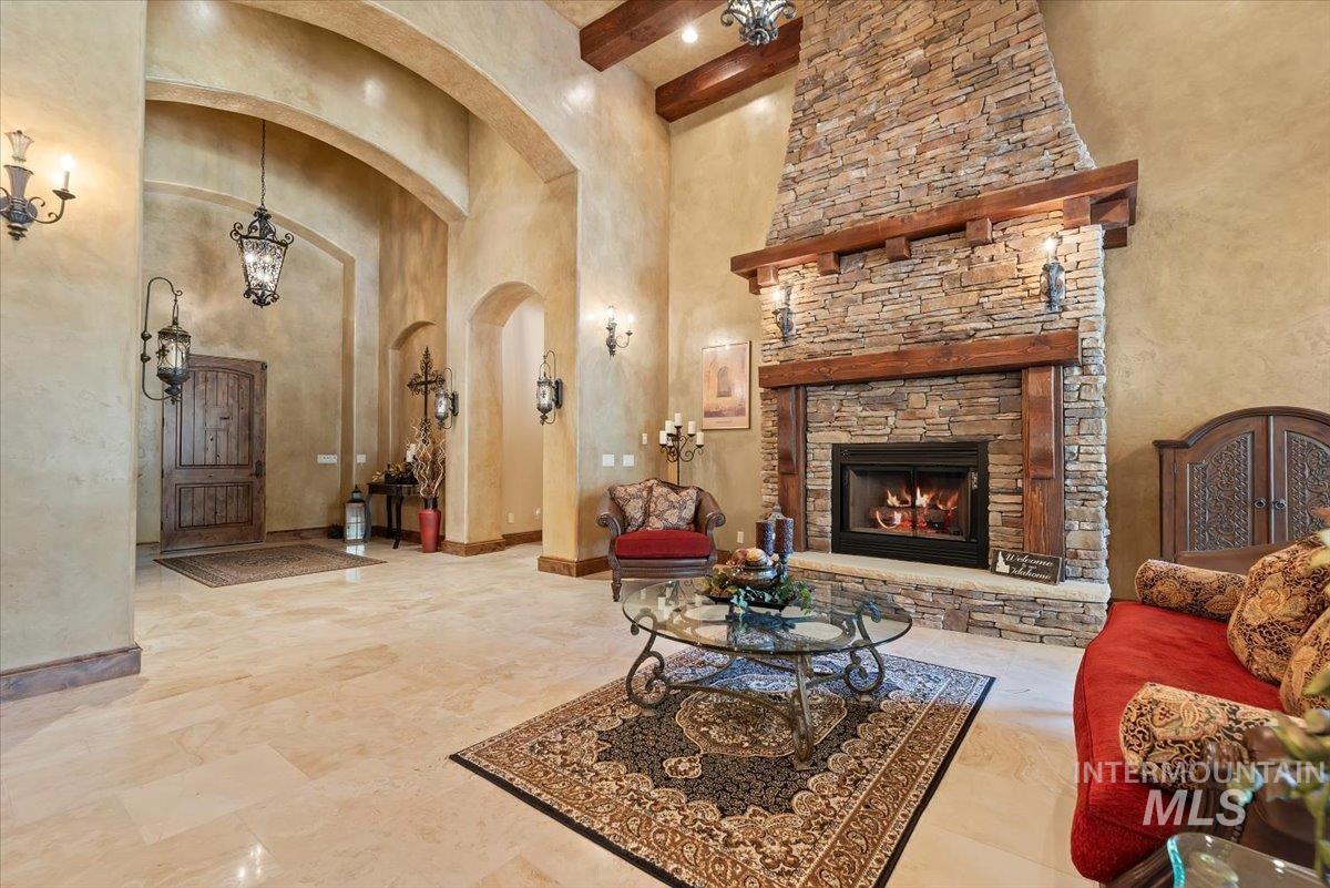 Living area with arched walkways, a towering ceiling, beam ceiling, and a fireplace
