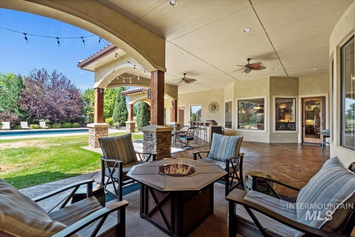 View of patio with a fire pit, an outdoor pool, and a ceiling fan