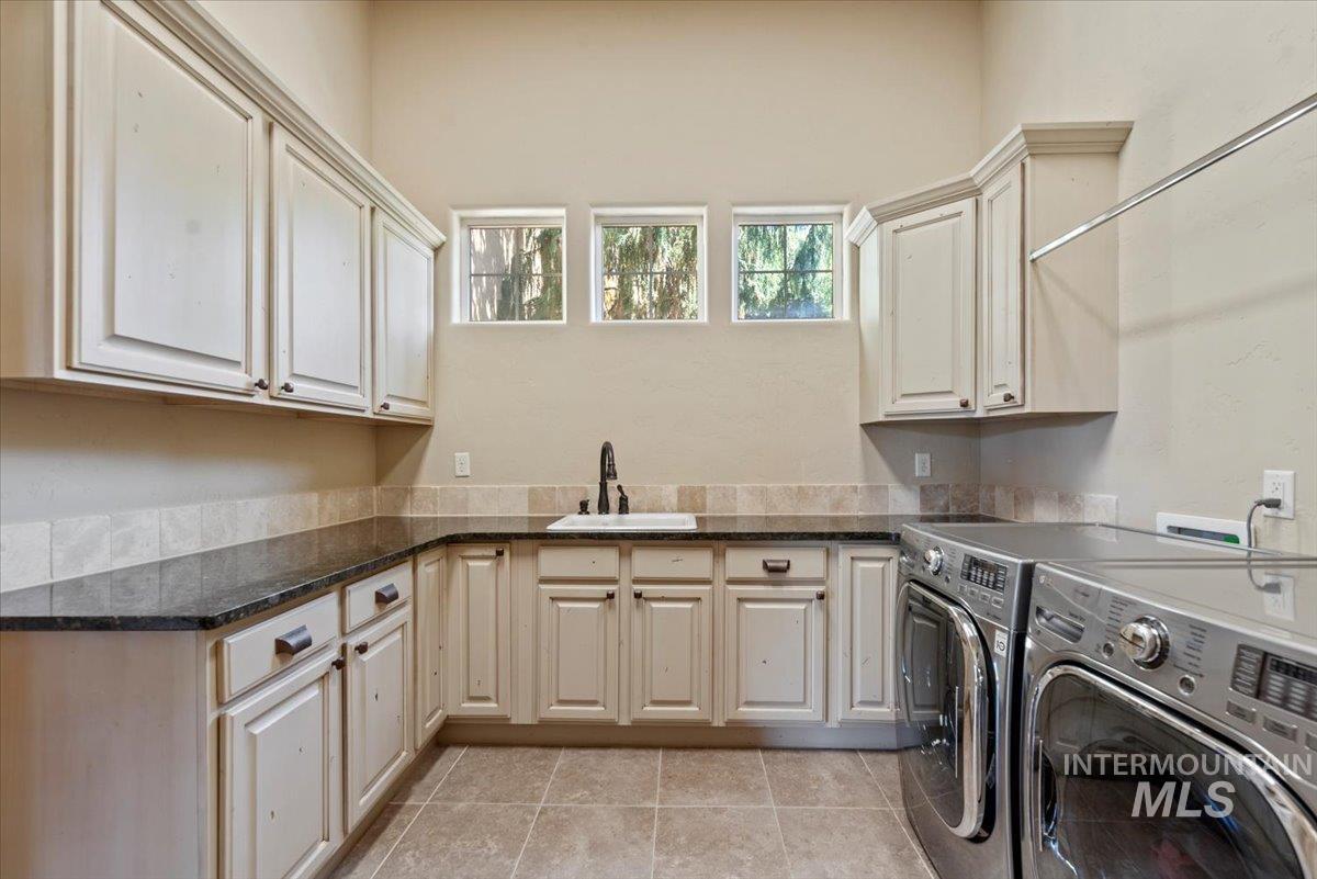 Laundry area with cabinet space, washing machine and dryer, and light tile patterned floors