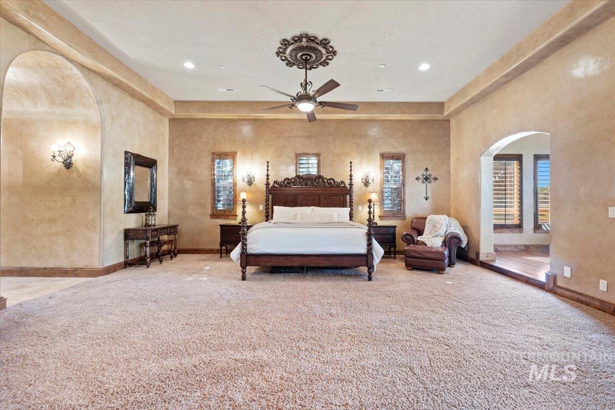 Bedroom featuring arched walkways, multiple windows, carpet, and recessed lighting