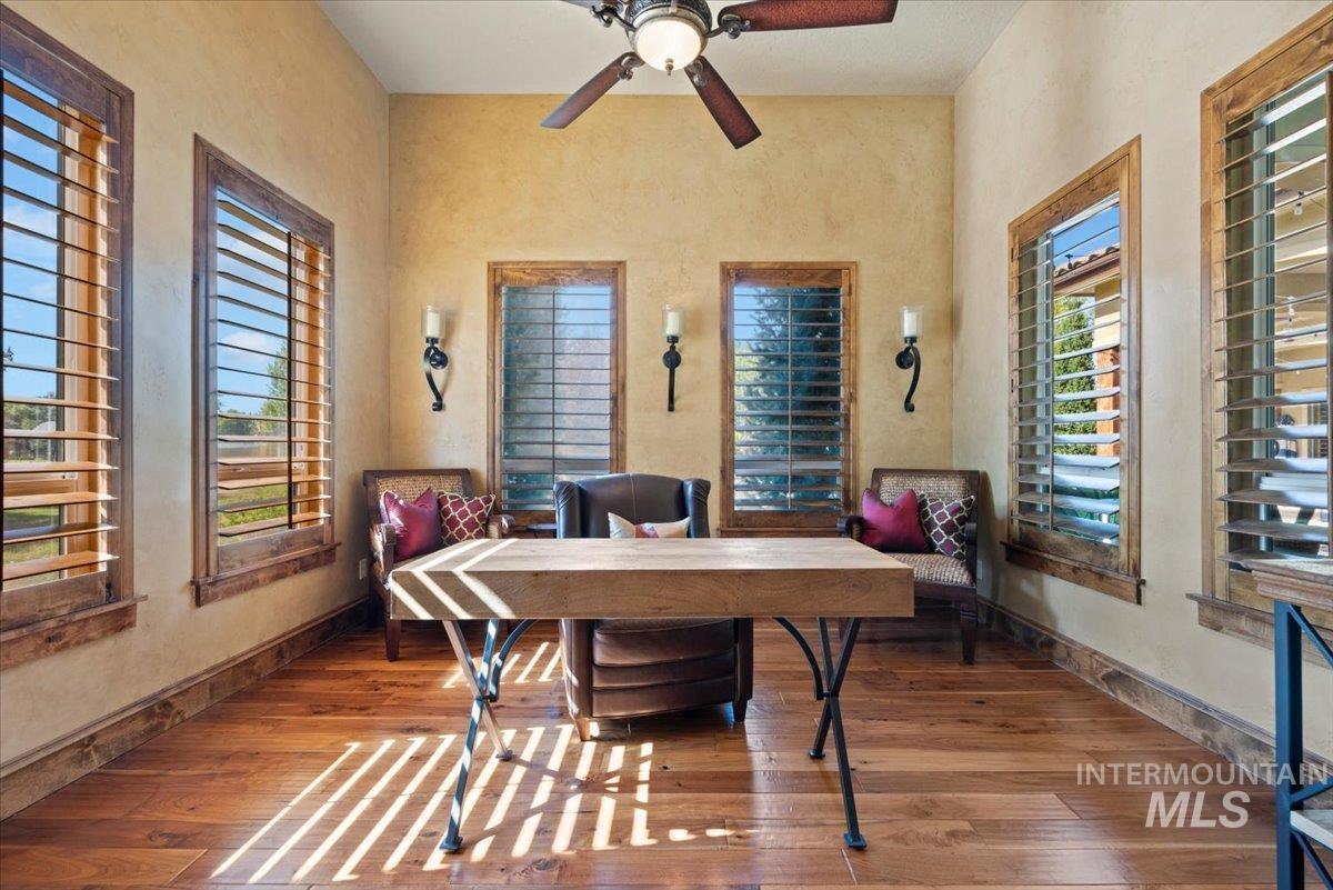 Office space featuring wood finished floors, ceiling fan, and a towering ceiling
