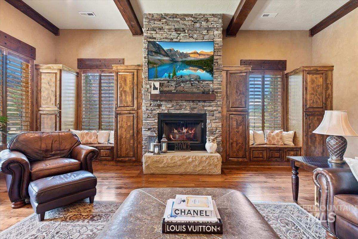 Living area with beam ceiling, hardwood / wood-style floors, and a fireplace