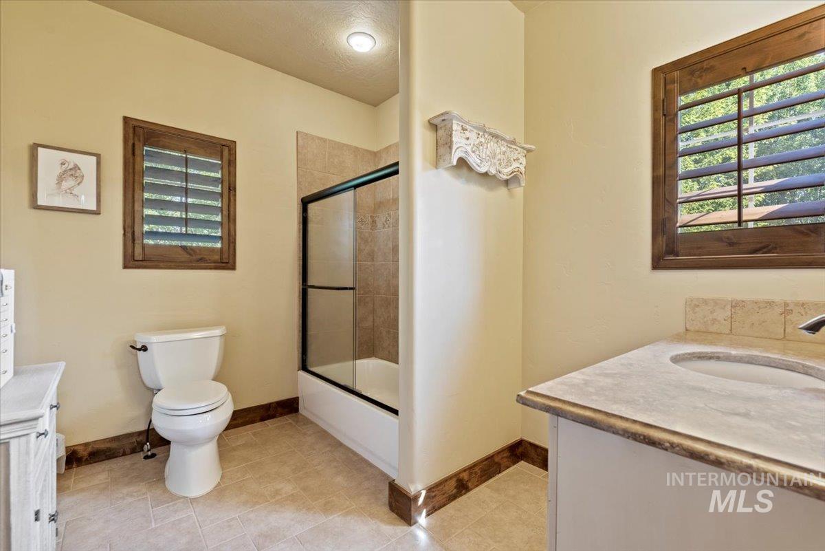 Full bath featuring vanity, enclosed tub / shower combo, and tile patterned floors