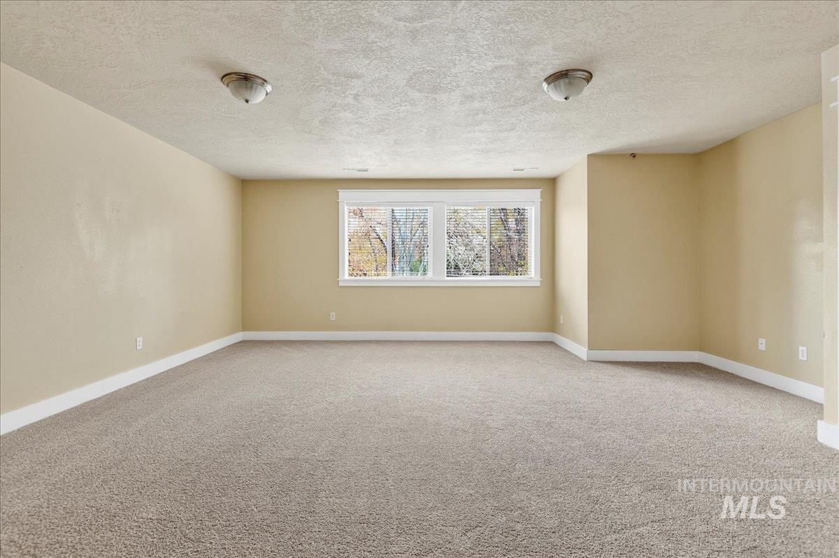 Empty room featuring light carpet and a textured ceiling