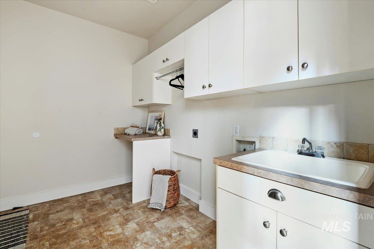 Laundry area featuring washer hookup, cabinet space, electric dryer hookup, and stone finish floors