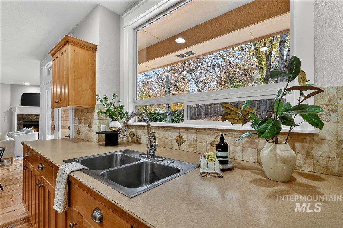 Kitchen featuring light countertops, a warm lit fireplace, backsplash, brown cabinets, and open floor plan