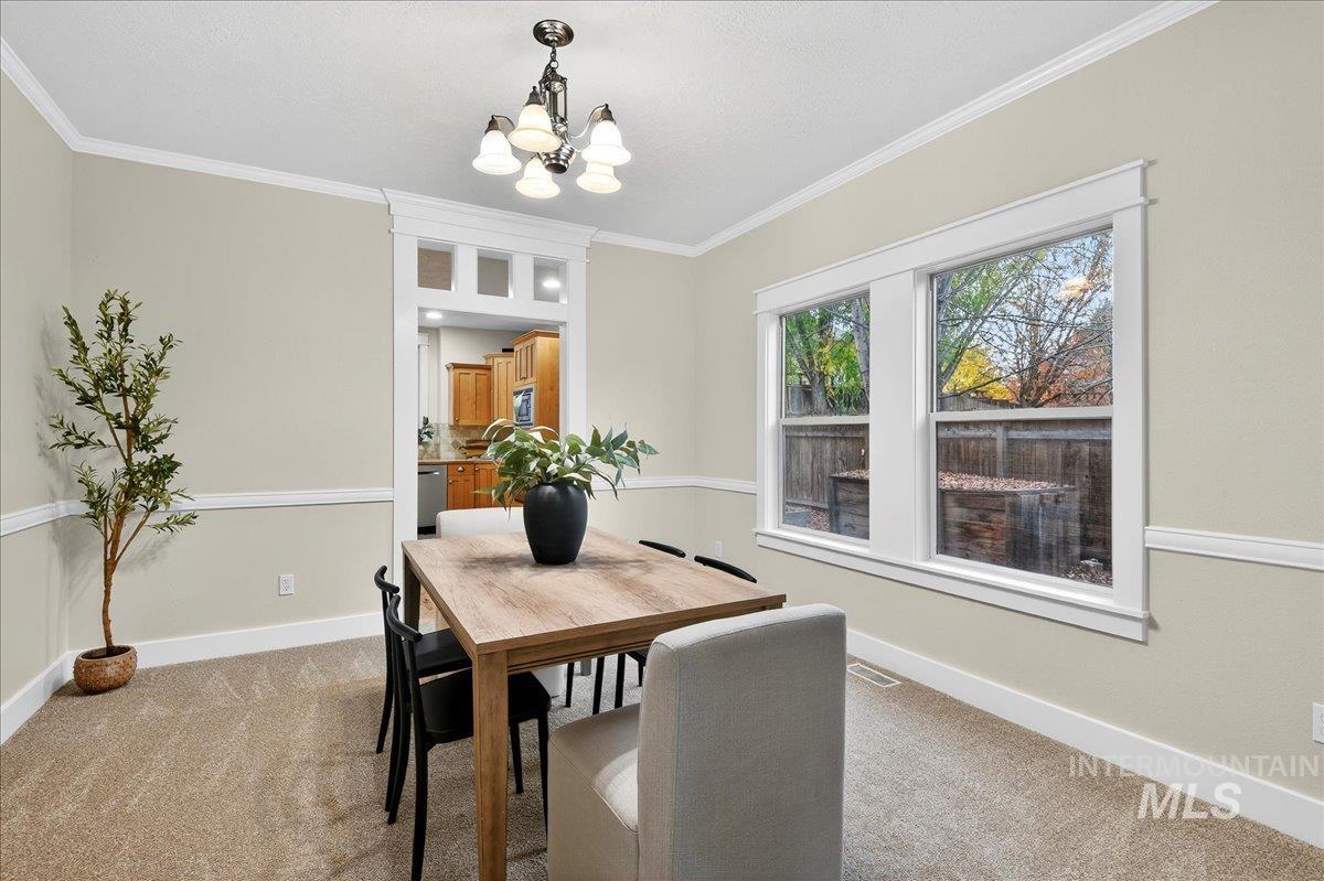 Dining area featuring crown molding, light carpet, and a chandelier