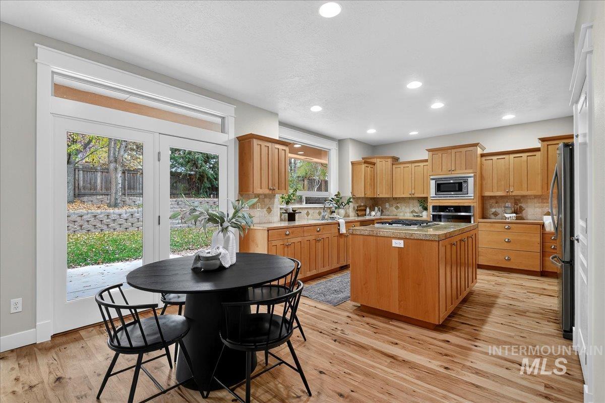 Kitchen featuring a center island, decorative backsplash, light wood-type flooring, appliances with stainless steel finishes, and recessed lighting