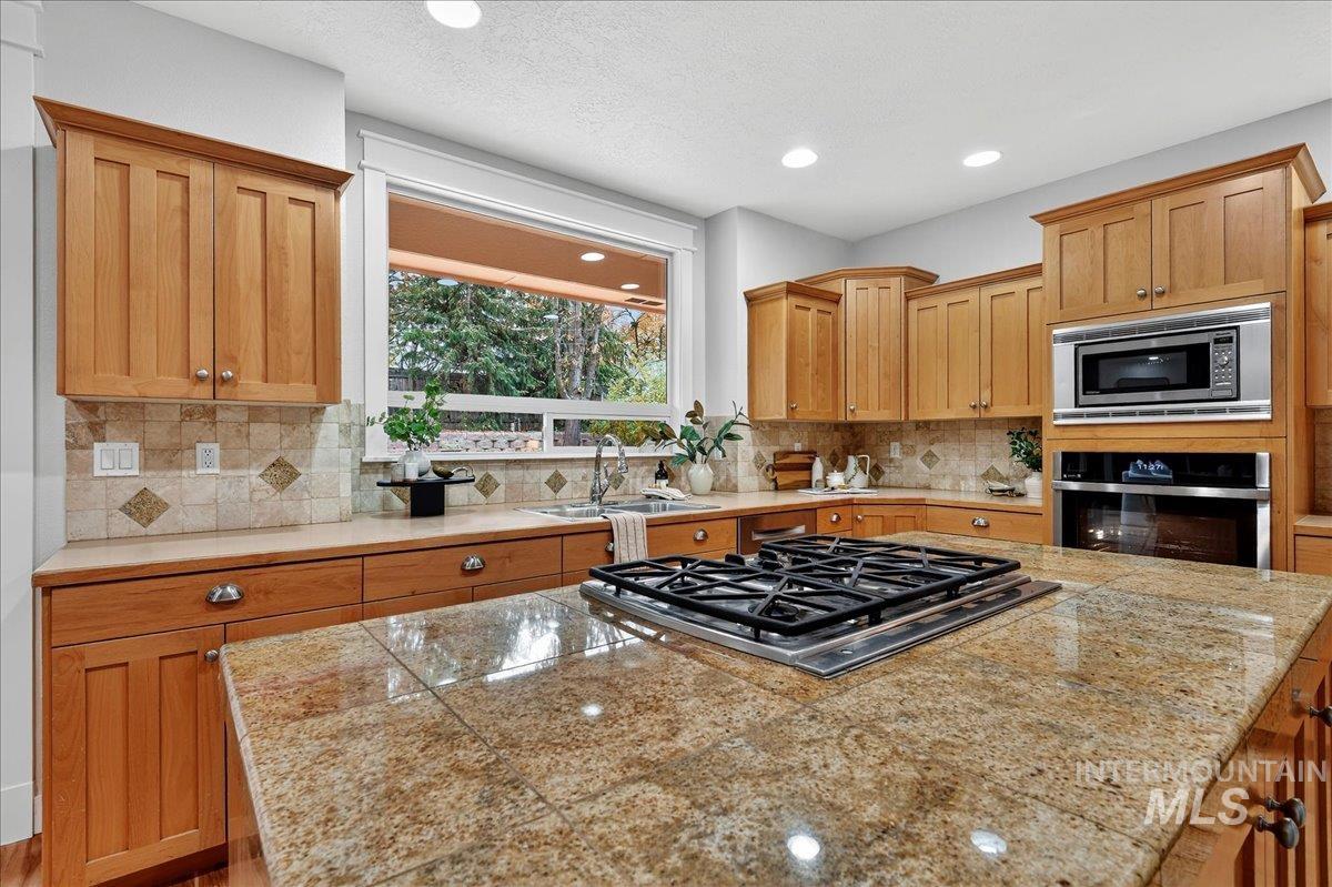 Kitchen featuring stainless steel appliances, backsplash, recessed lighting, a center island, and tile countertops