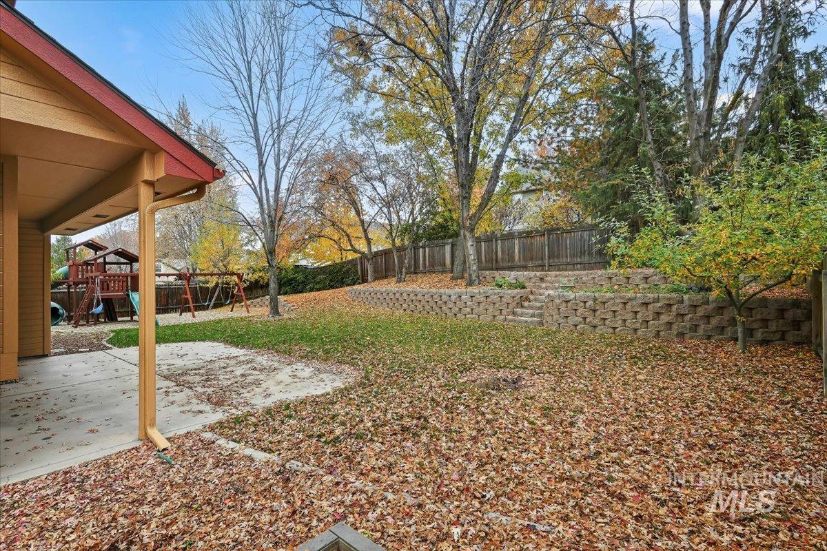 Fenced backyard featuring a playground and a patio