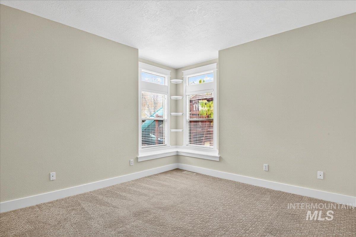 Unfurnished room with a textured ceiling and carpet flooring