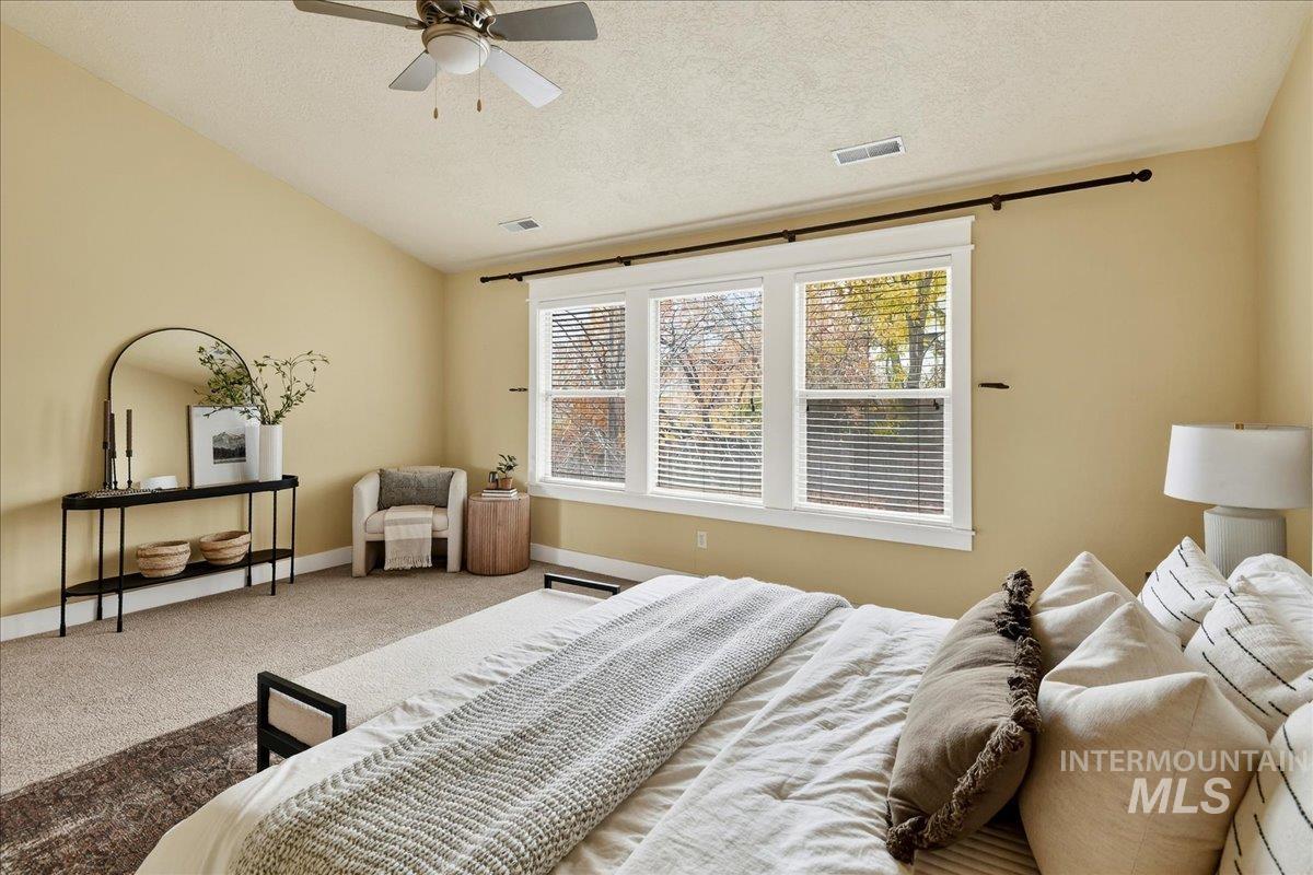 Carpeted bedroom featuring a textured ceiling and a ceiling fan