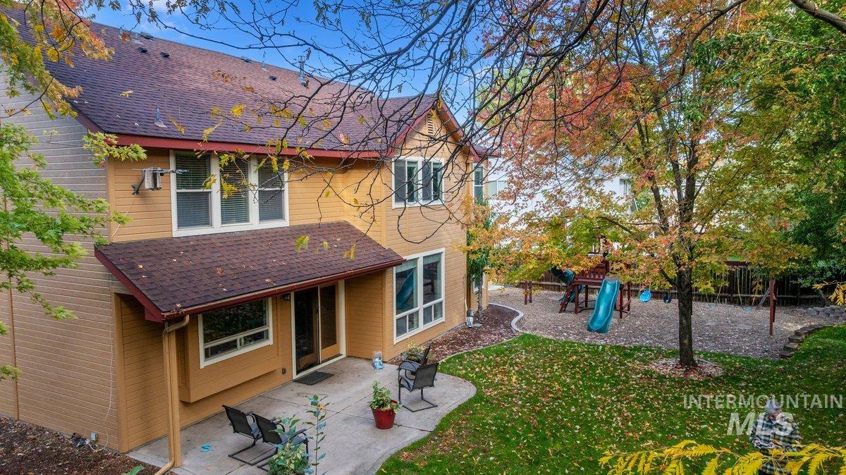 Rear view of house with roof with shingles, a patio, a playground, and a lawn