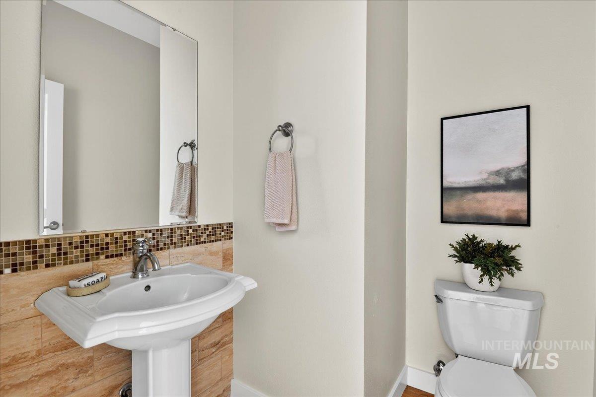 Half bathroom with toilet and tasteful backsplash