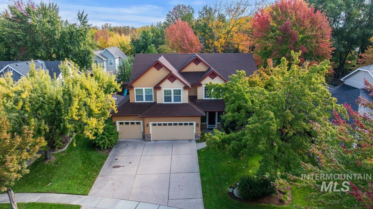 Craftsman house with stone siding, concrete driveway, an attached garage, roof with shingles, and a front lawn