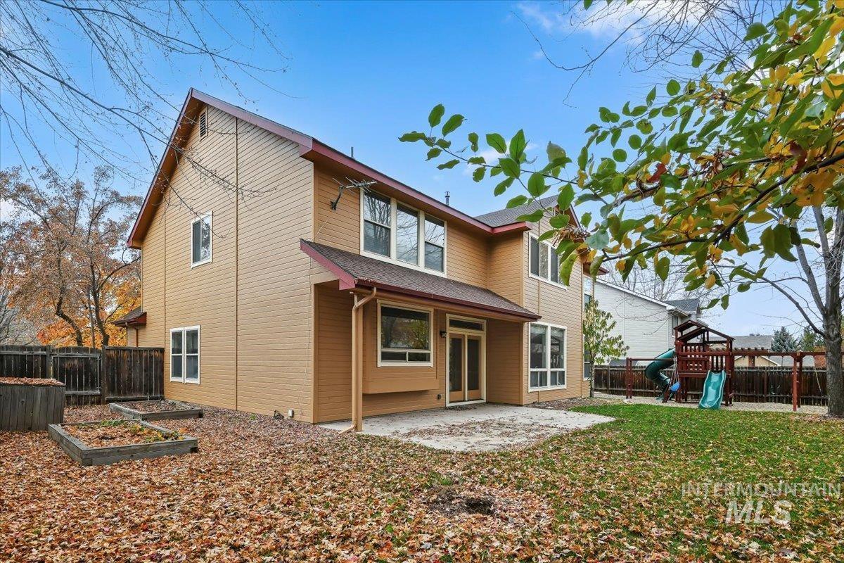 Back of house featuring a fenced backyard, a patio area, a playground, and a vegetable garden