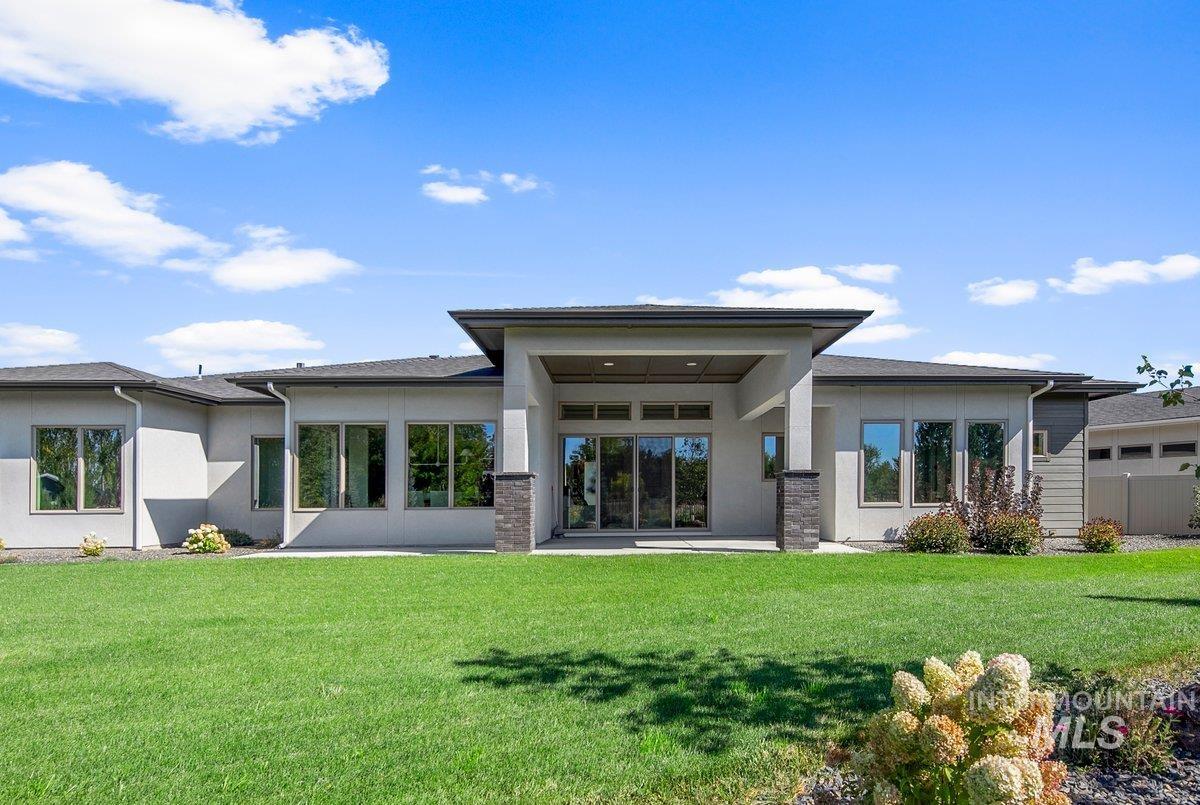 Back of house with stucco siding, a patio area, and a yard