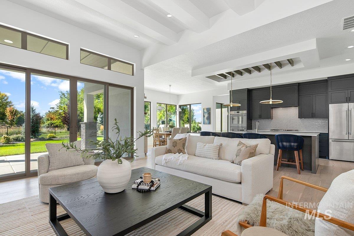 Living area featuring beamed ceiling, light wood finished floors, recessed lighting, and a towering ceiling