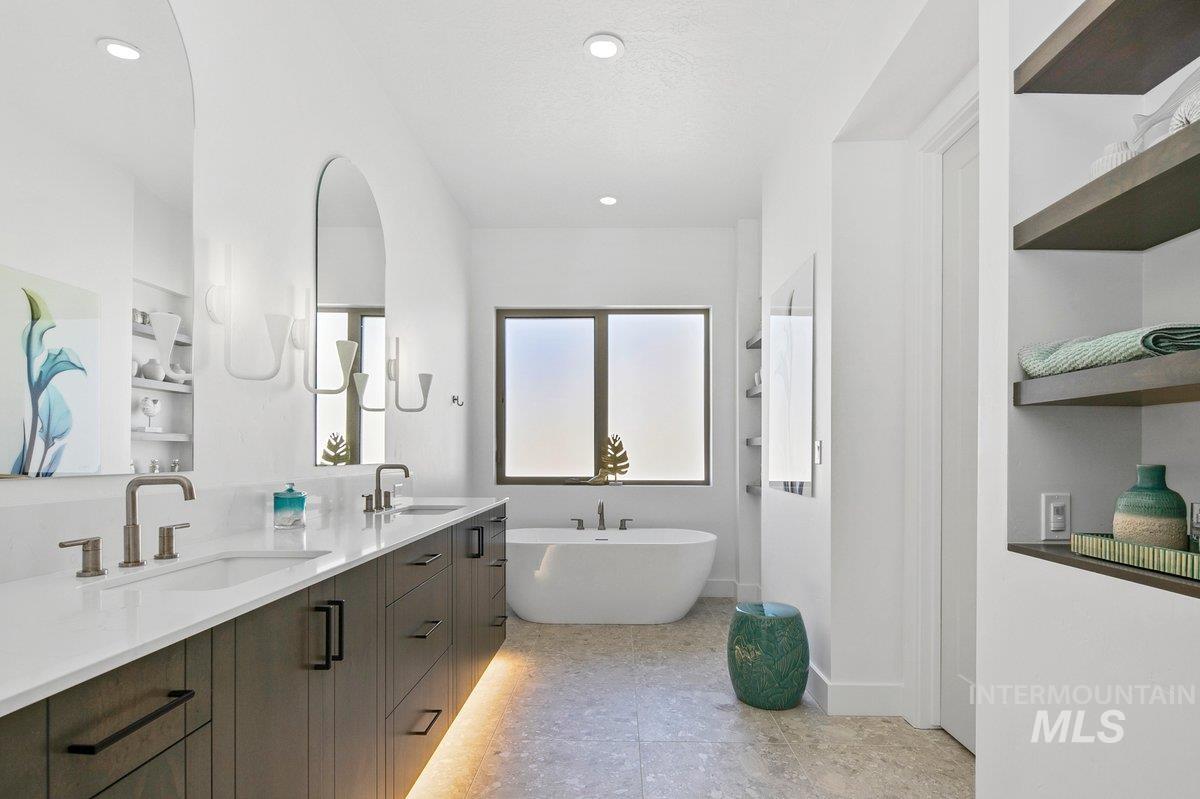 Full bath with a freestanding tub, double vanity, built in features, and recessed lighting