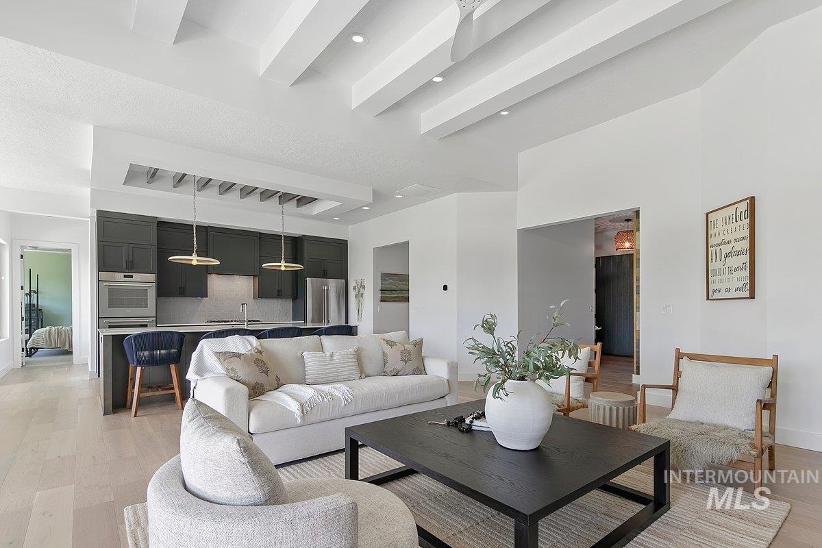 Living room with light wood finished floors and beam ceiling