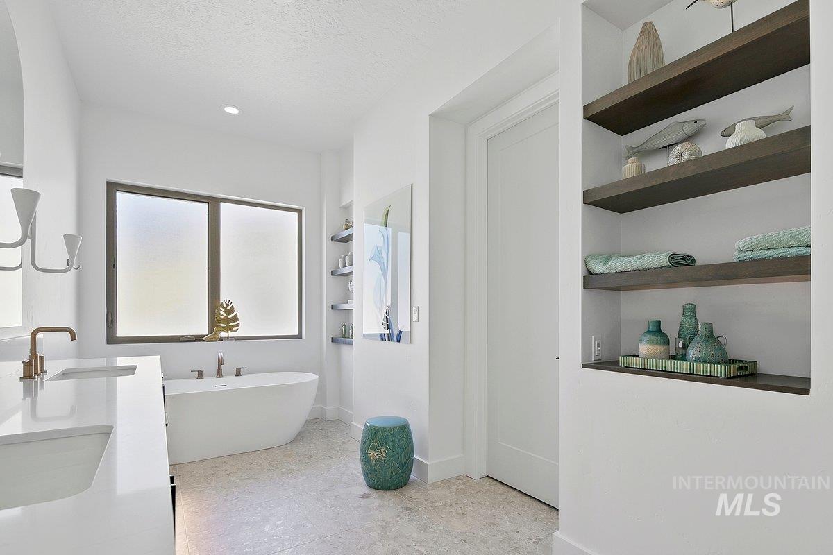 Full bath featuring a soaking tub, built in shelves, double vanity, a textured ceiling, and recessed lighting