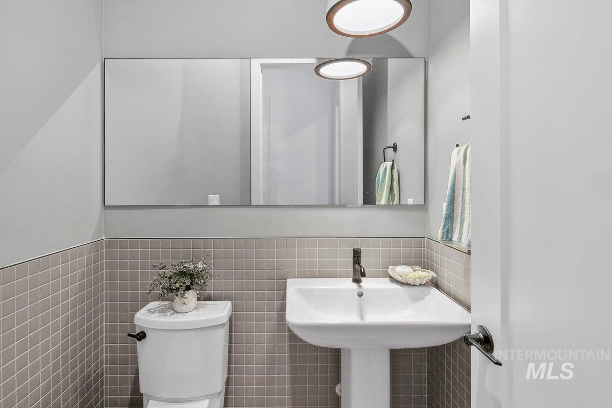 Half bath featuring tile walls and a wainscoted wall
