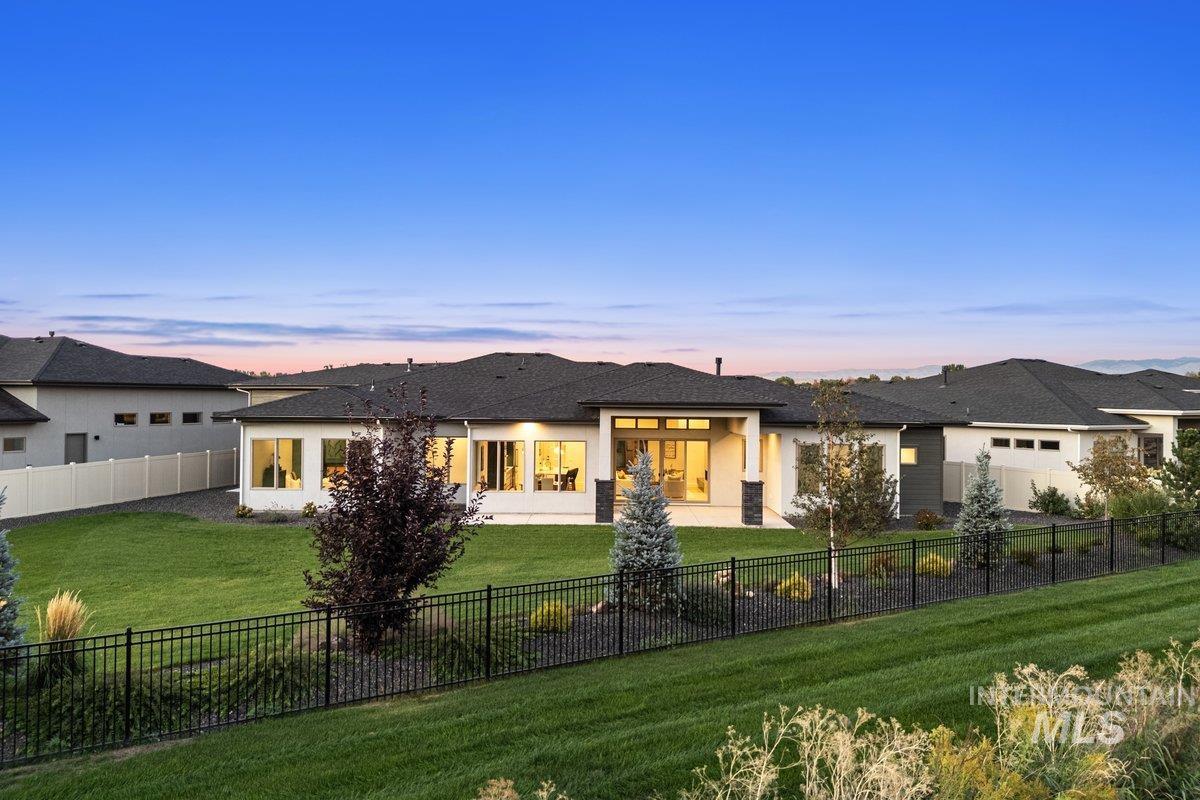 Back of property at dusk with a fenced backyard, a patio area, and stucco siding