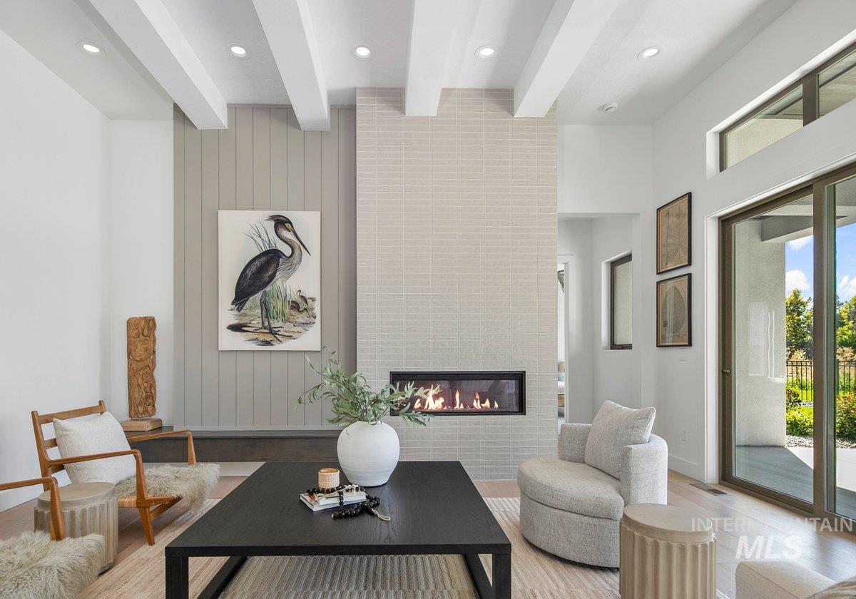 Living room with wood finished floors, beamed ceiling, a large fireplace, and recessed lighting