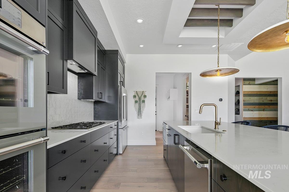 Kitchen featuring stainless steel appliances, light wood-style floors, recessed lighting, hanging light fixtures, and backsplash