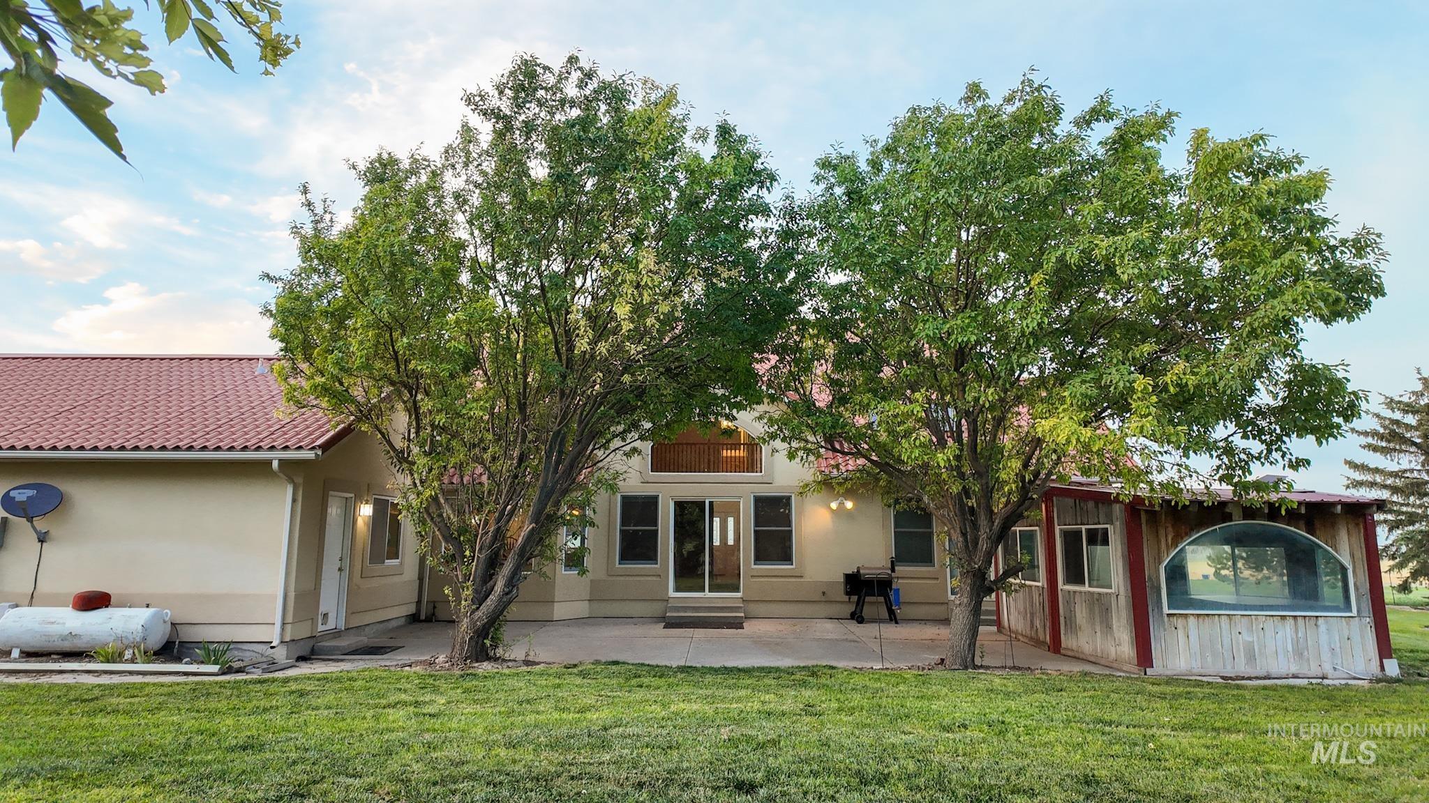 Rear view of property with a patio area, a lawn, entry steps, and stucco siding