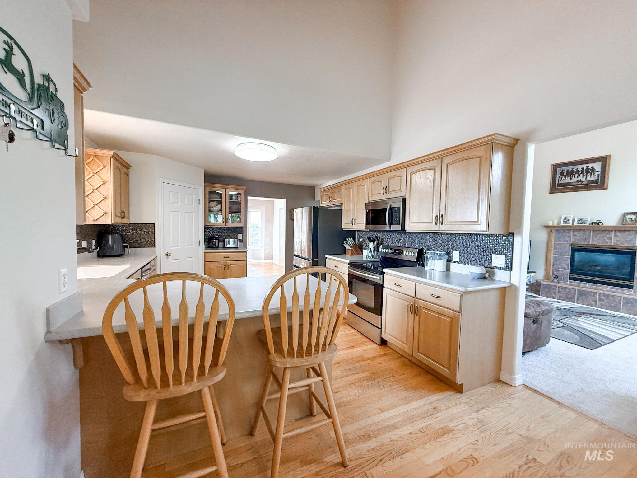 Kitchen featuring a peninsula, stainless steel appliances, light brown cabinets, a breakfast bar area, and light wood-style flooring