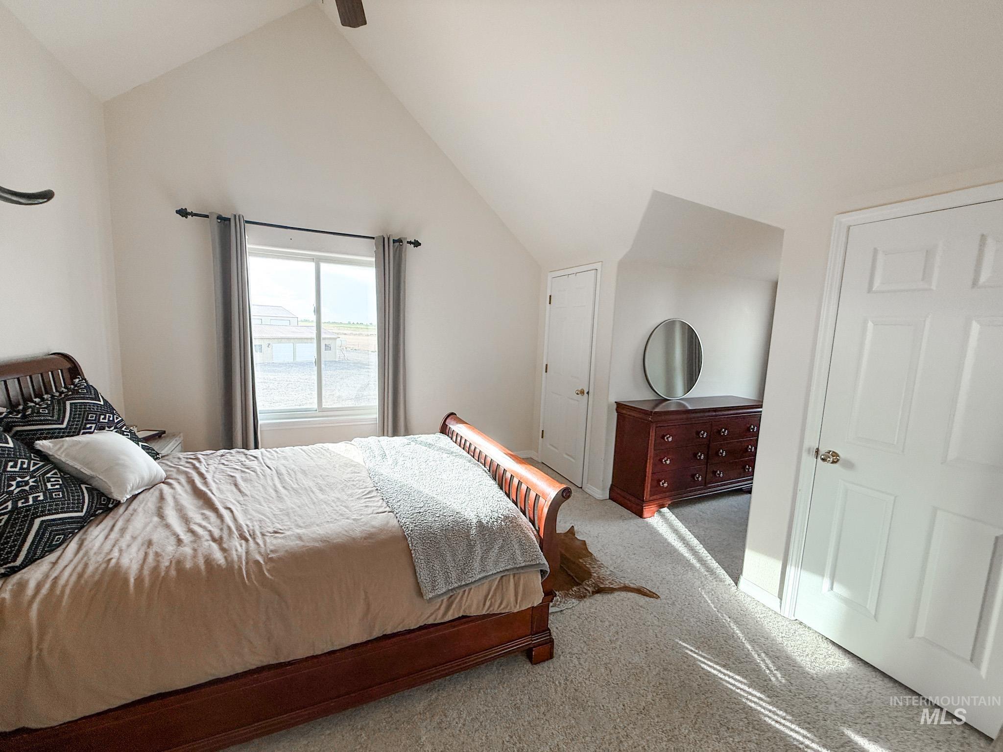 Carpeted bedroom with baseboards and high vaulted ceiling