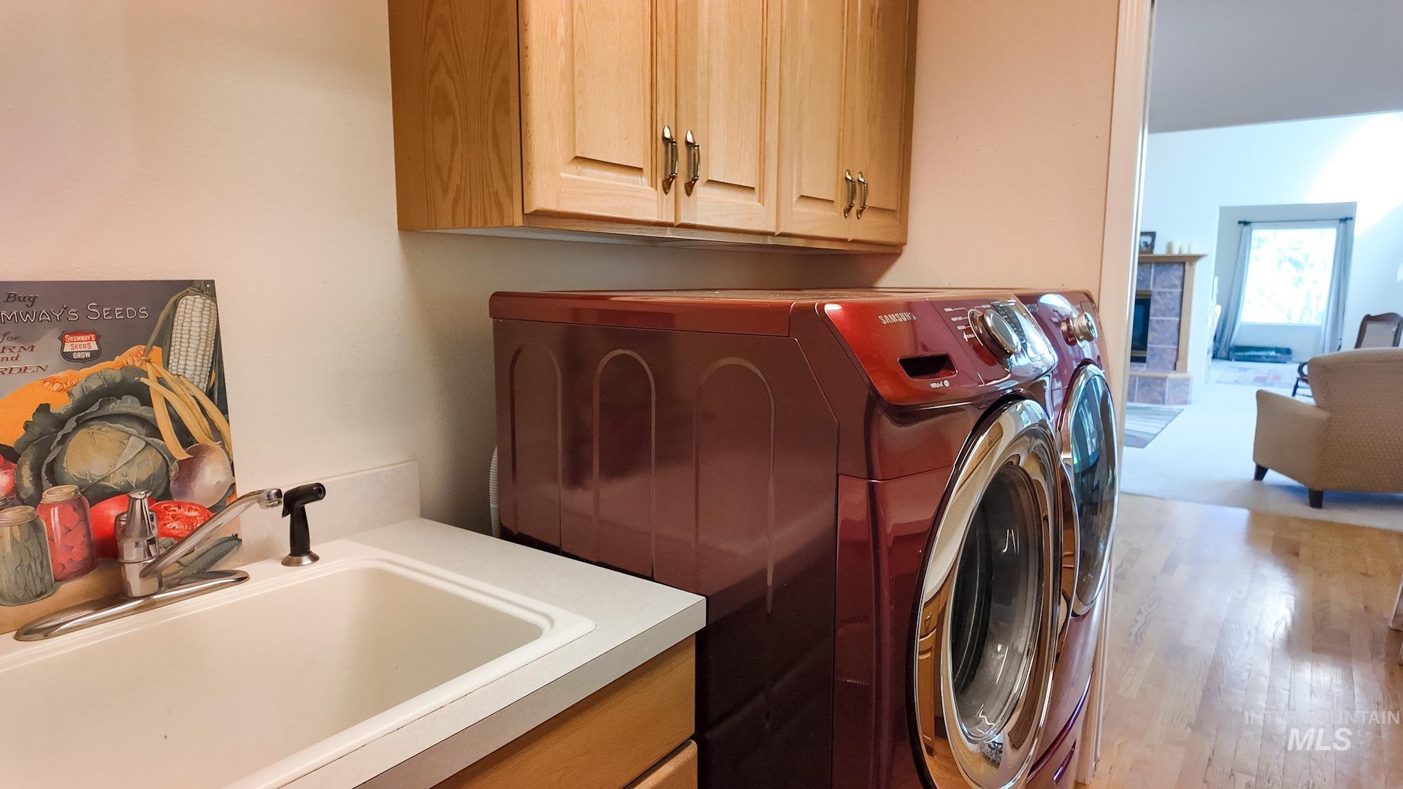 Laundry room featuring cabinet space, washing machine and dryer, wood finished floors.