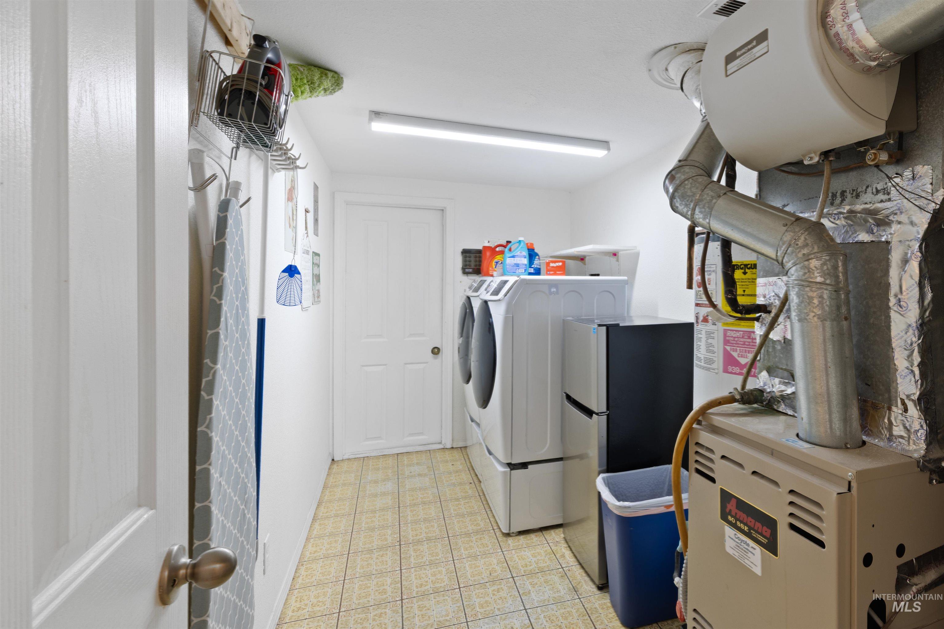 Laundry room with heating unit and washing machine and clothes dryer