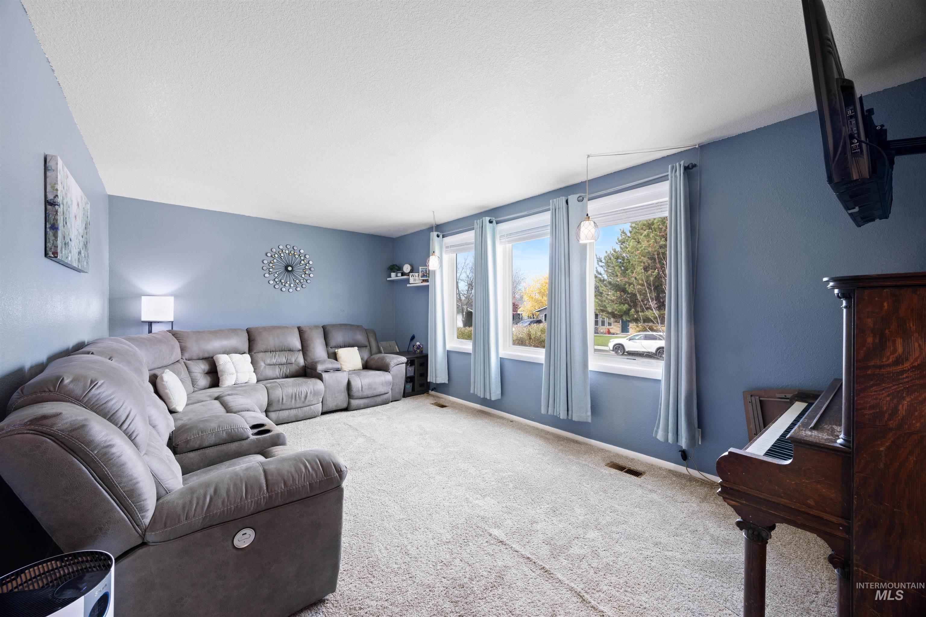Carpeted living room with a textured ceiling and baseboards