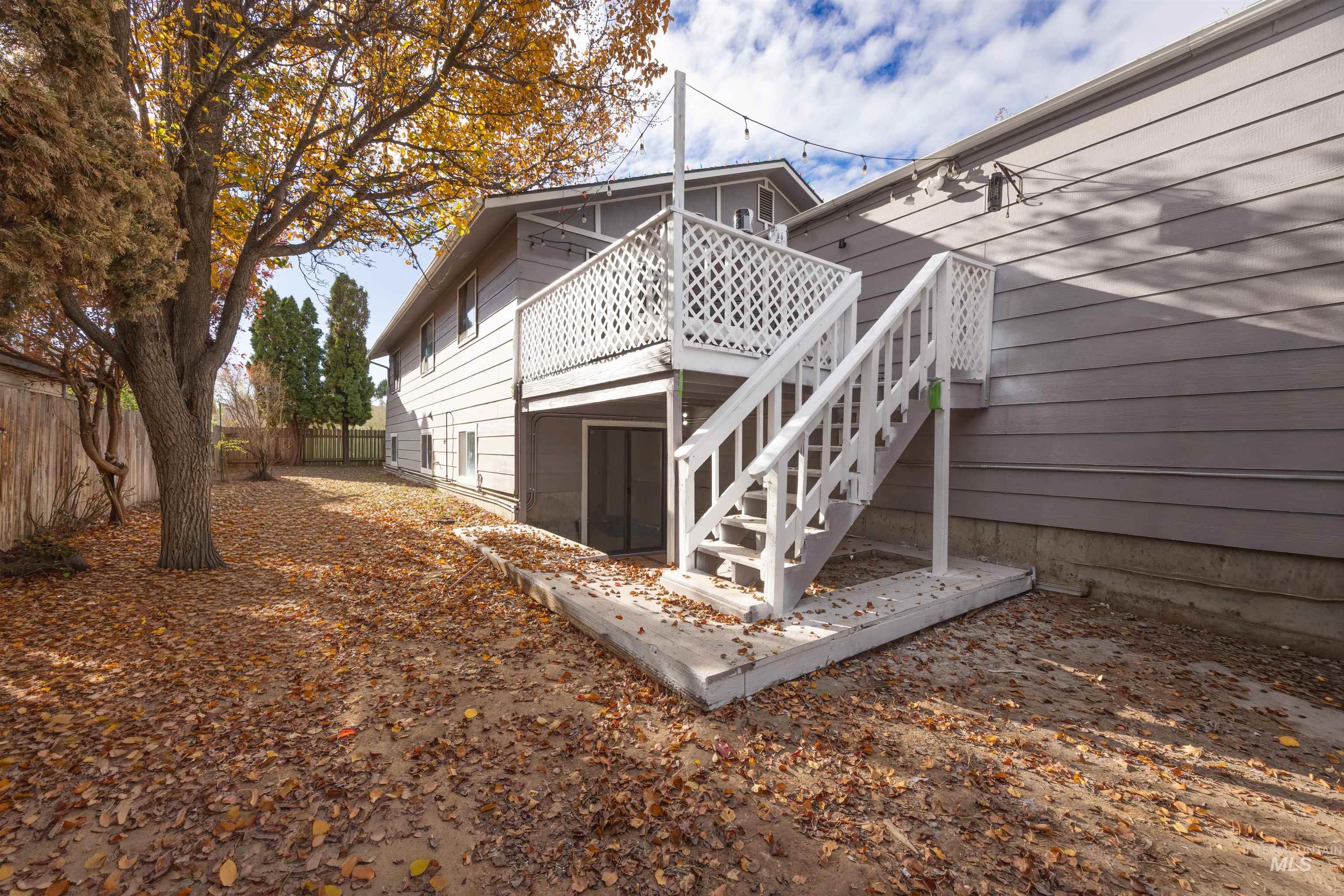 Back of house with a deck, a fenced backyard, and stairway