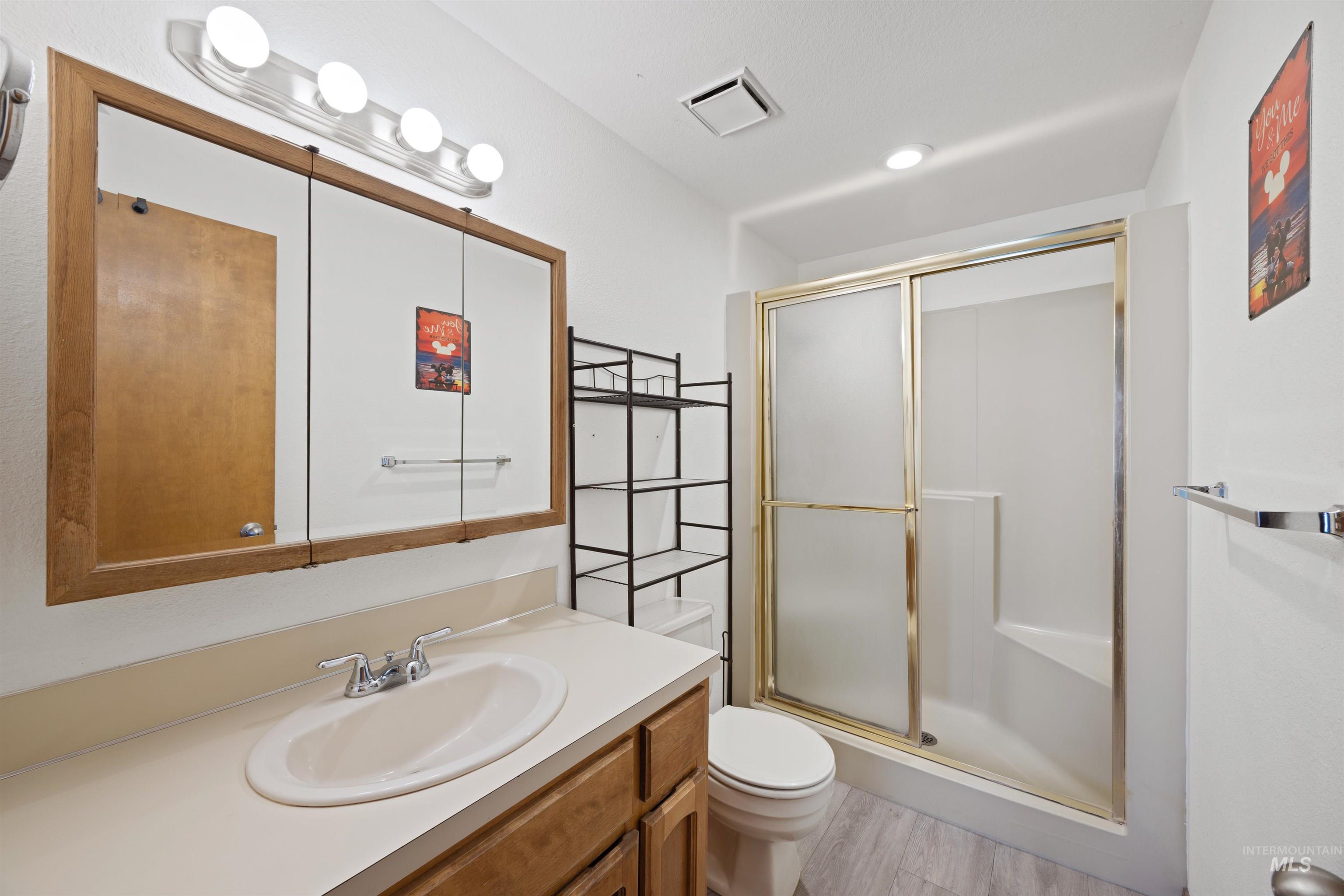 Full bath featuring a stall shower, vanity, and light wood finished floors