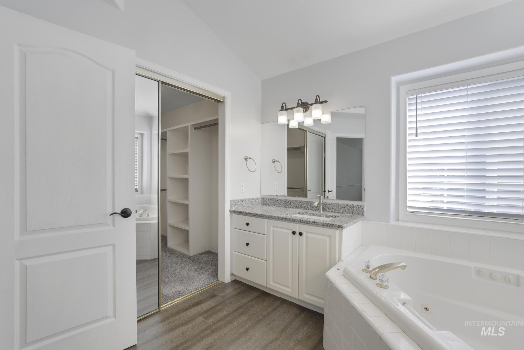 Full bath featuring vanity, a bath, dark wood-style flooring, a closet, and lofted ceiling
